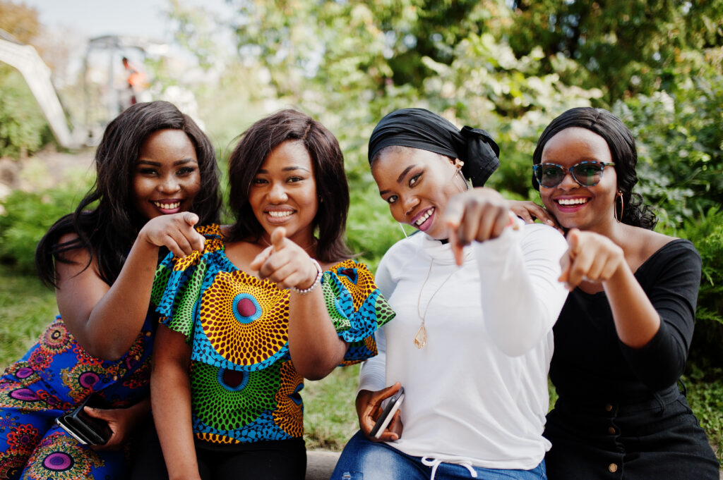group of four african american girls sitting outdoor and showing